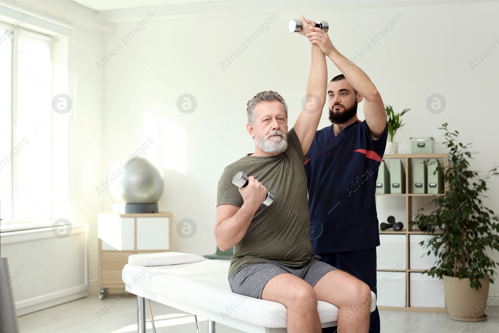 Photo of Physiotherapist working with patient in clinic. Rehabilitation therapy