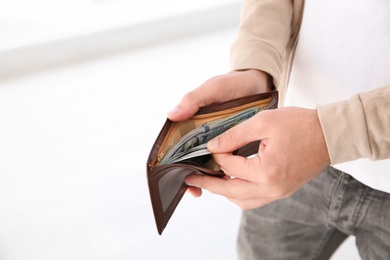 Photo of Man holding wallet with money indoors, closeup. Space for text