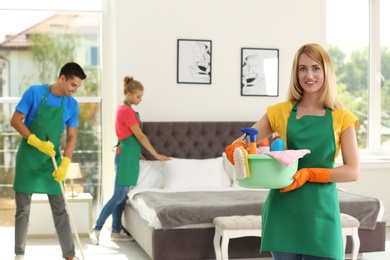 Photo of Team of professional janitors in uniform cleaning bedroom