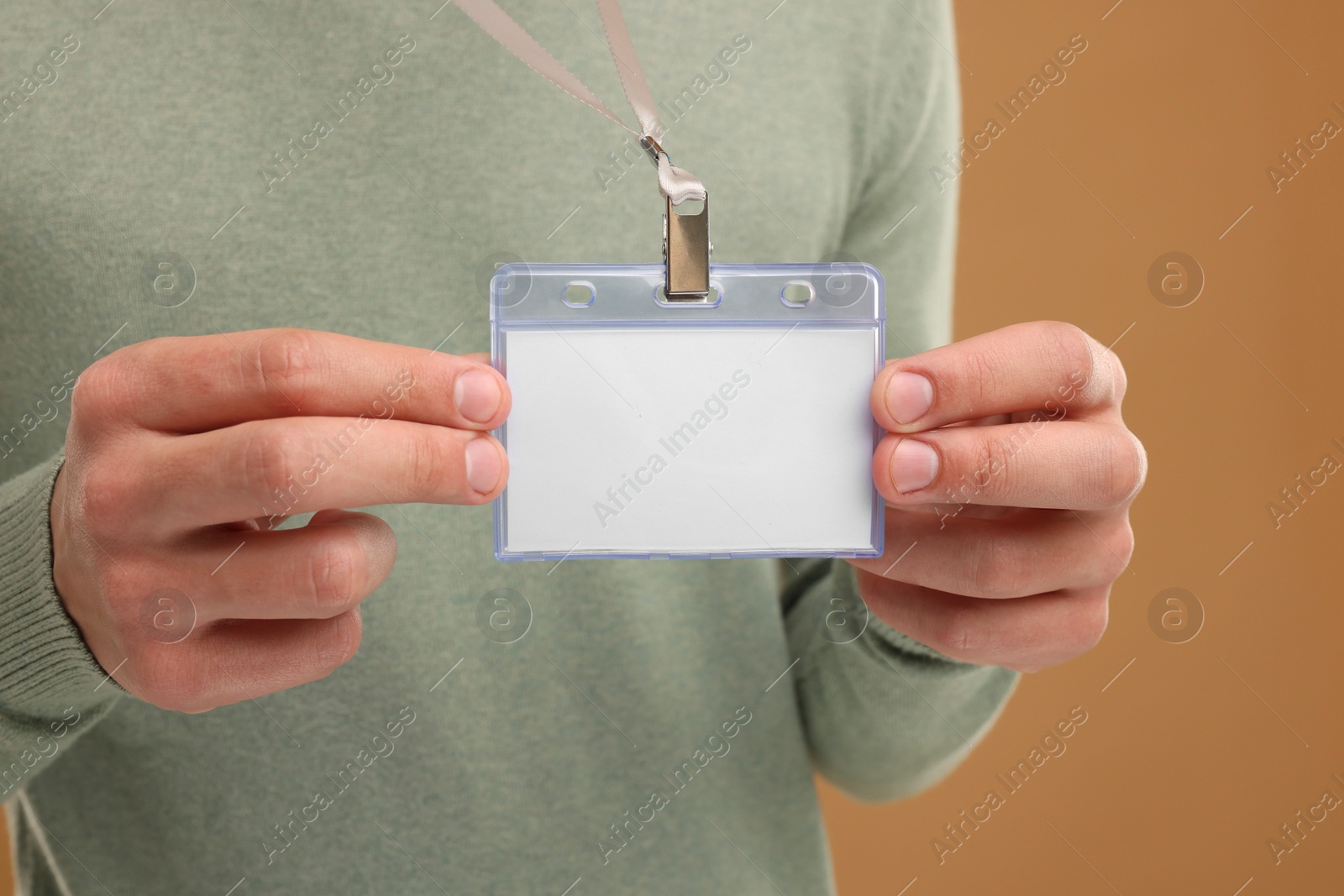 Photo of Man with blank badge on light brown background, closeup