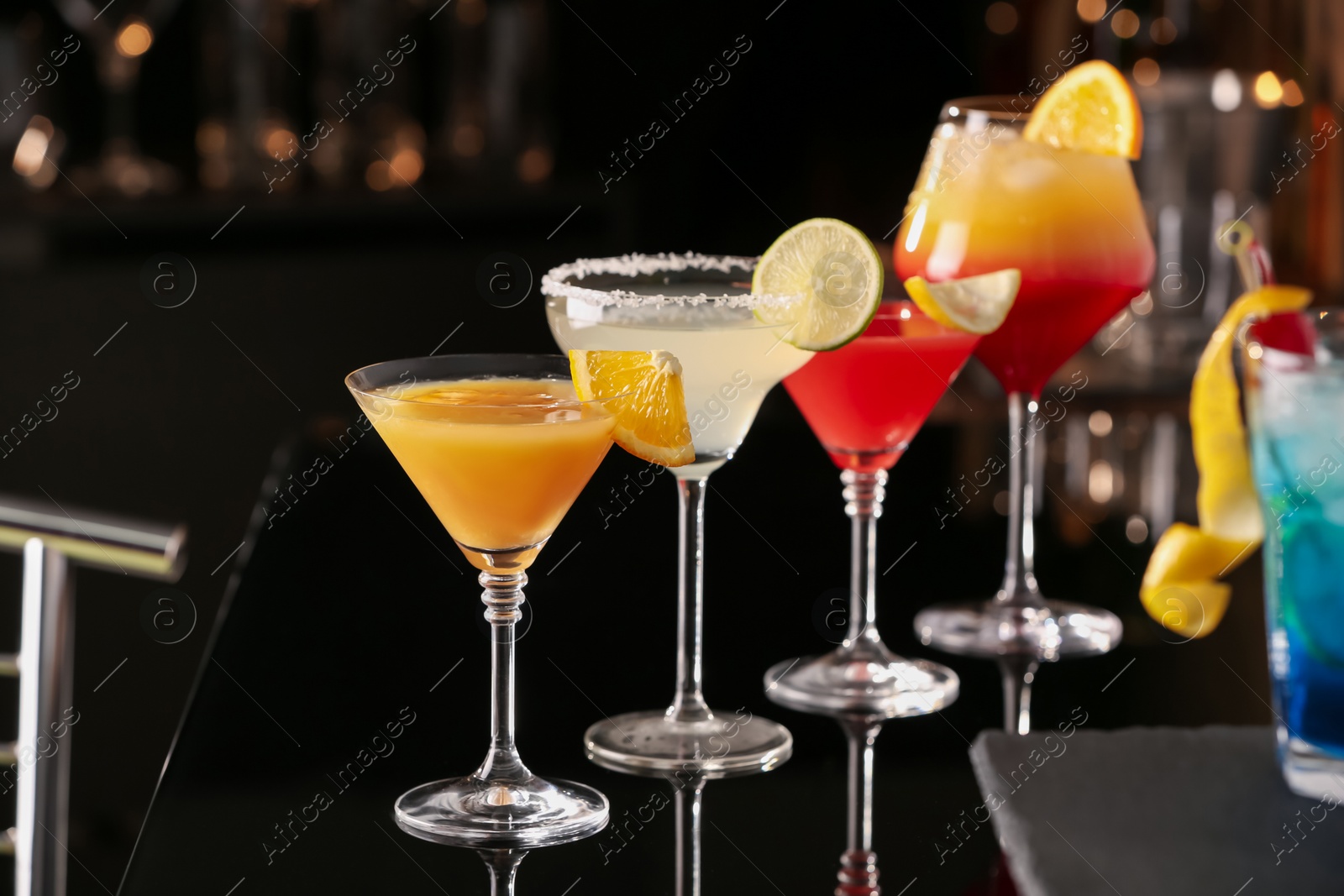 Photo of Different delicious cocktails on black table in bar