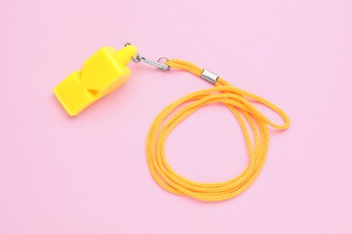 Photo of One yellow whistle with orange cord on pink background, top view