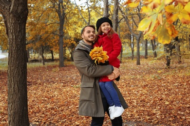 Father and his cute daughter spending time together in park. Autumn walk