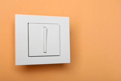 Photo of White light switch on orange background, space for text