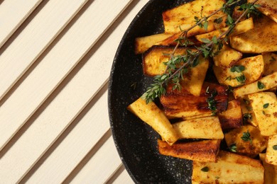 Photo of Delicious parsnips with thyme in frying pan on white wooden table, top view