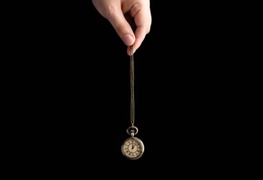 Psychotherapist with pendulum on black background, closeup. Hypnotherapy session