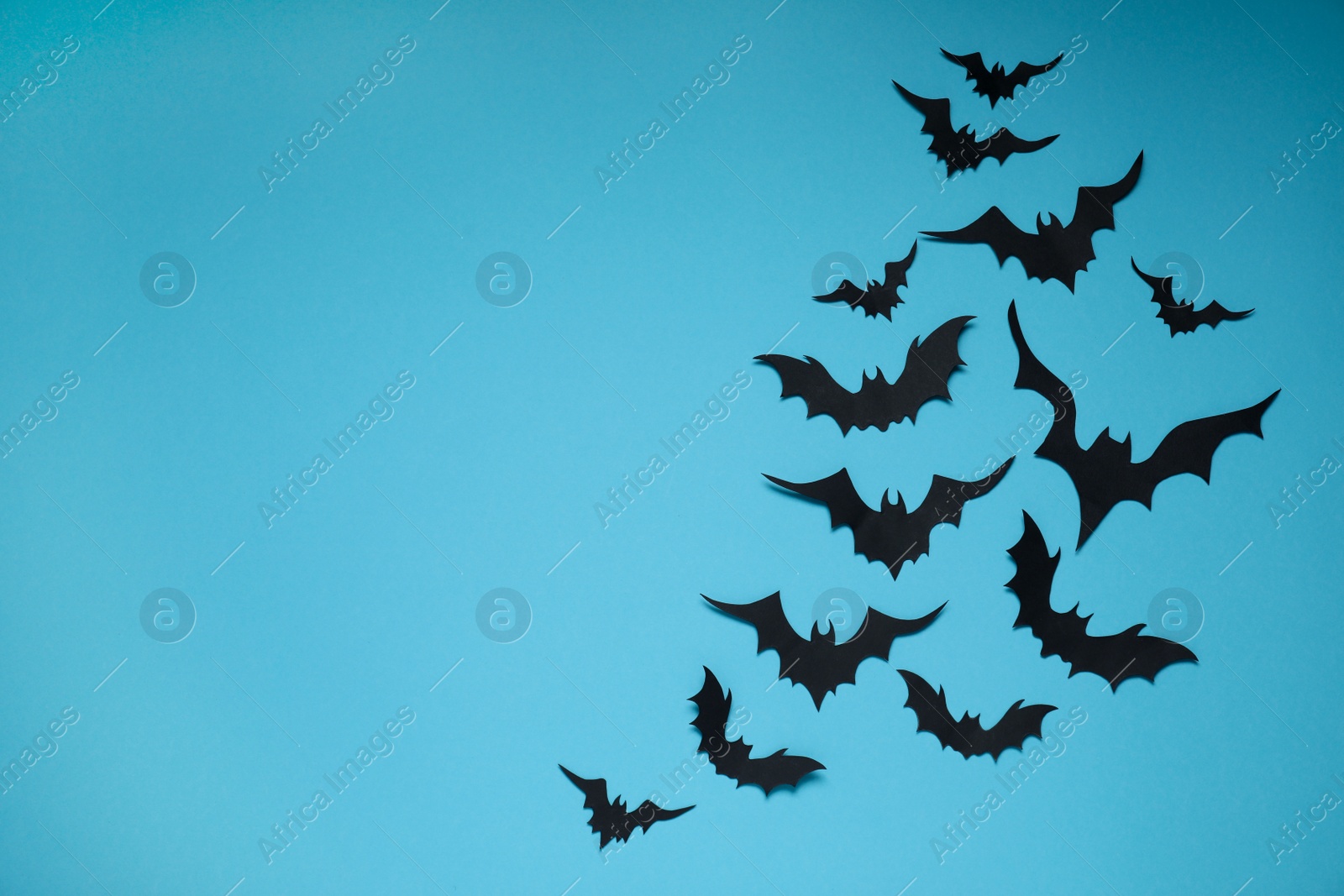 Photo of Flat lay composition with paper bats on light blue background, space for text. Halloween decor