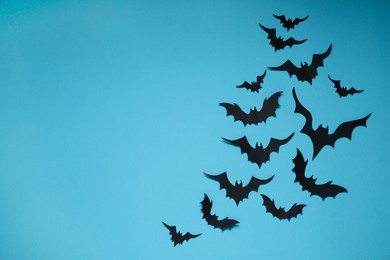 Flat lay composition with paper bats on light blue background, space for text. Halloween decor