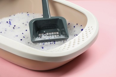 Photo of Cat litter tray with filler and scoop on pink background, closeup
