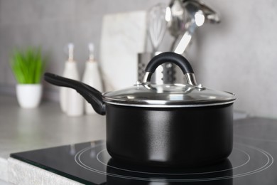 Photo of Saucepan with lid on cooktop in kitchen, closeup view. Cooking utensil