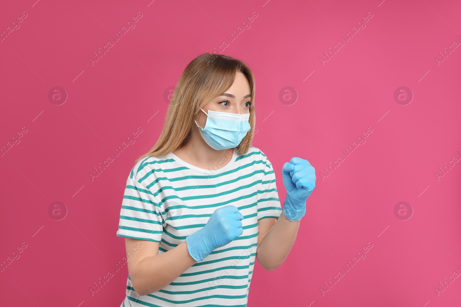 Photo of Woman with protective mask and gloves in fighting pose on pink background. Strong immunity concept