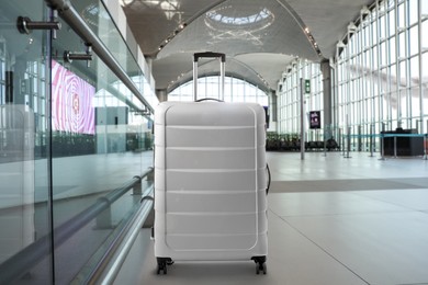 Image of Stylish light grey suitcase in airport terminal