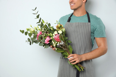 Photo of Florist with beautiful bouquet on light background, closeup