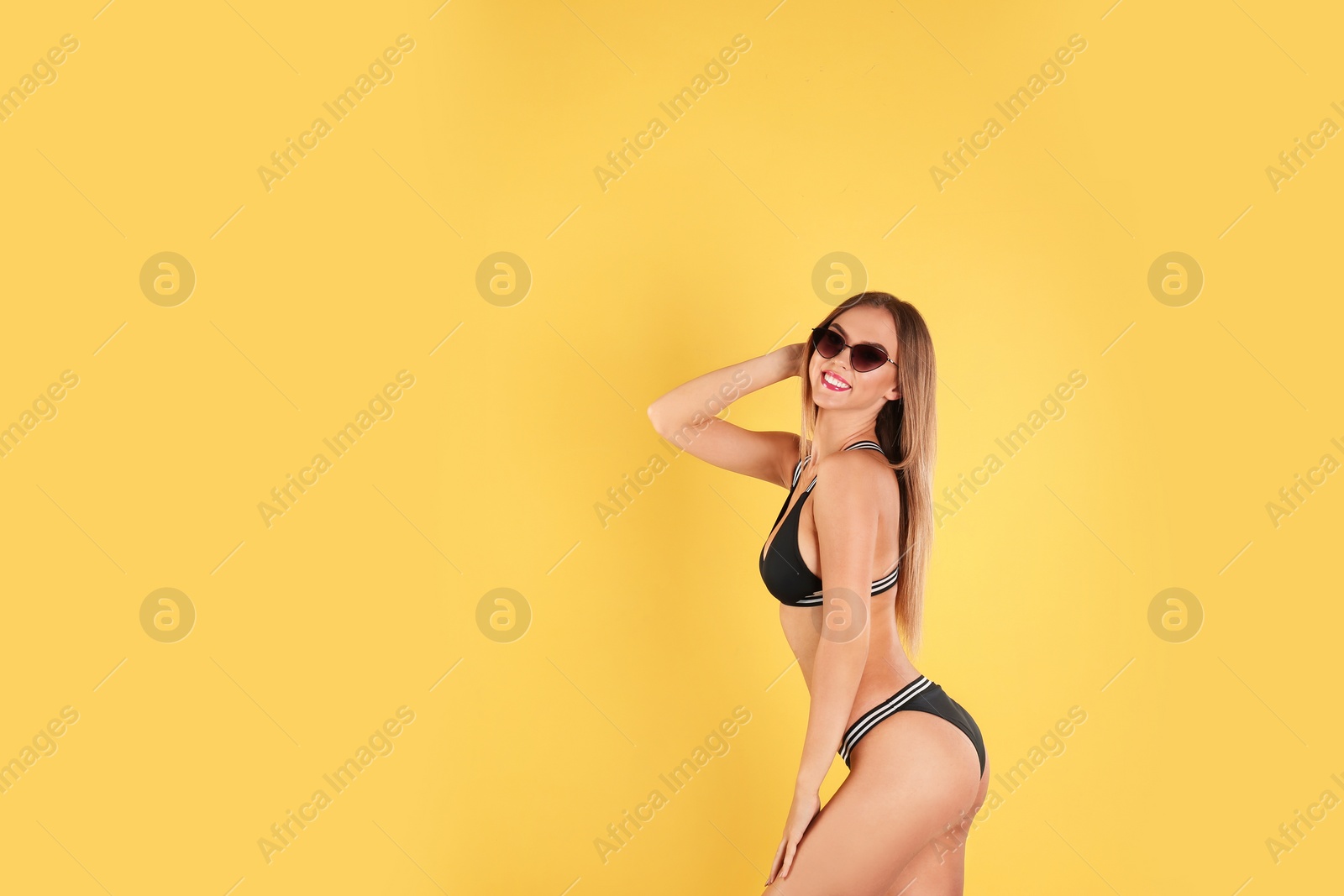 Photo of Pretty sexy woman in stylish bikini with sunglasses on color background