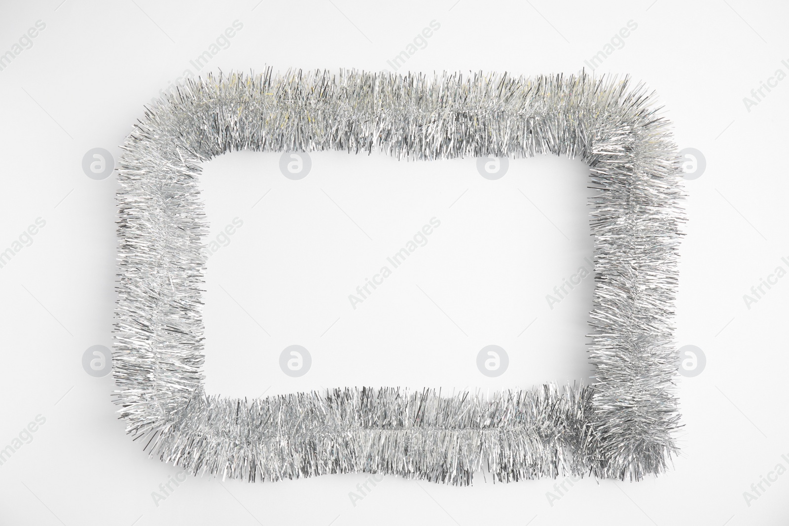 Photo of Frame of silver tinsel on white background, top view. Space for text