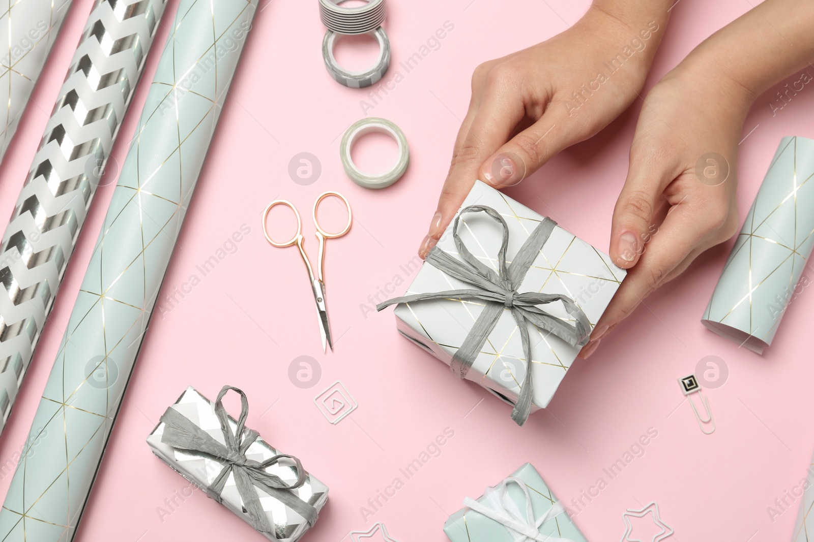 Photo of Woman with gift box and tools for decor on color background, view from above