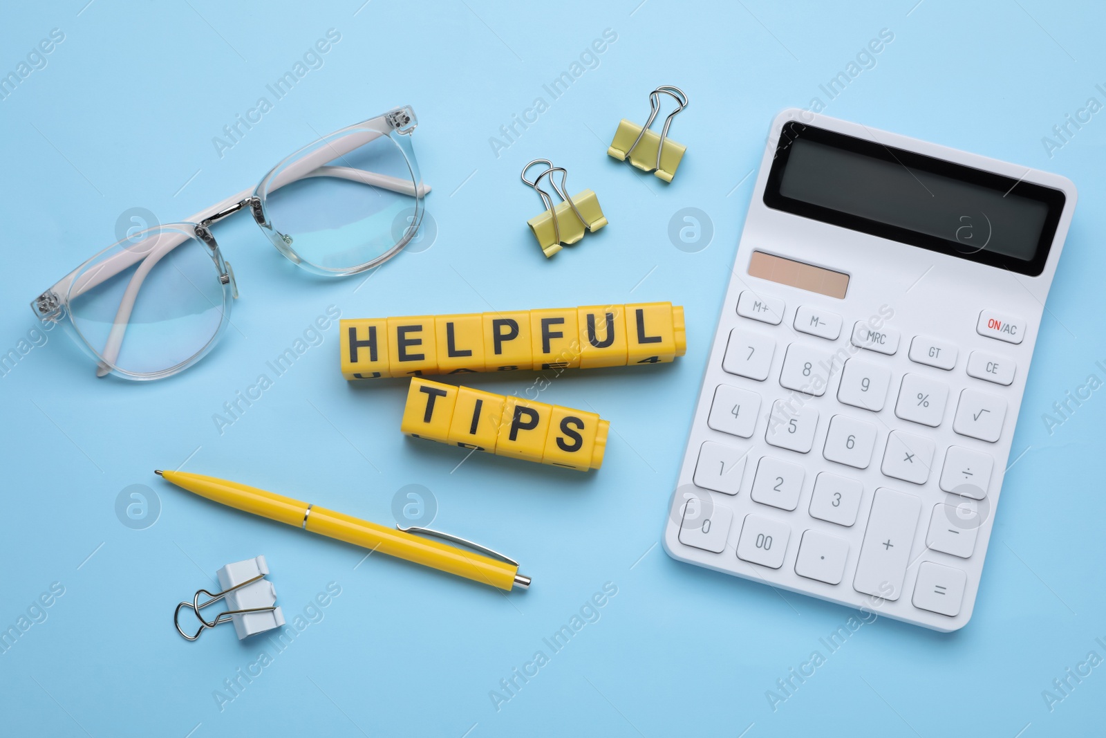 Photo of Flat lay composition with phrase Helpful Tips made of yellow cubes on light blue background