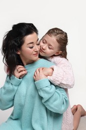 Photo of Beautiful mother hugging with little daughter on white background