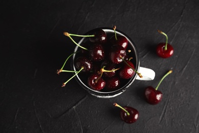 Mug with sweet red cherries on table, top view