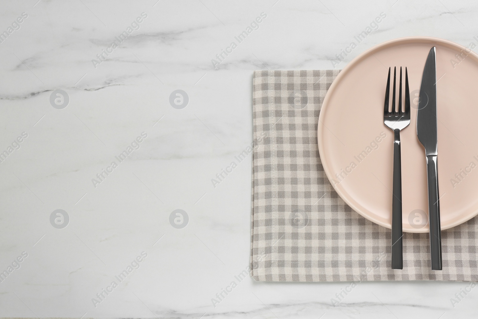 Photo of Clean plate with shiny silver cutlery on white marble table, flat lay. Space for text