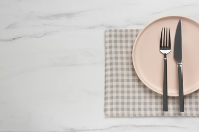 Photo of Clean plate with shiny silver cutlery on white marble table, flat lay. Space for text