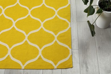 Yellow carpet with geometric pattern on wooden floor in room, above view