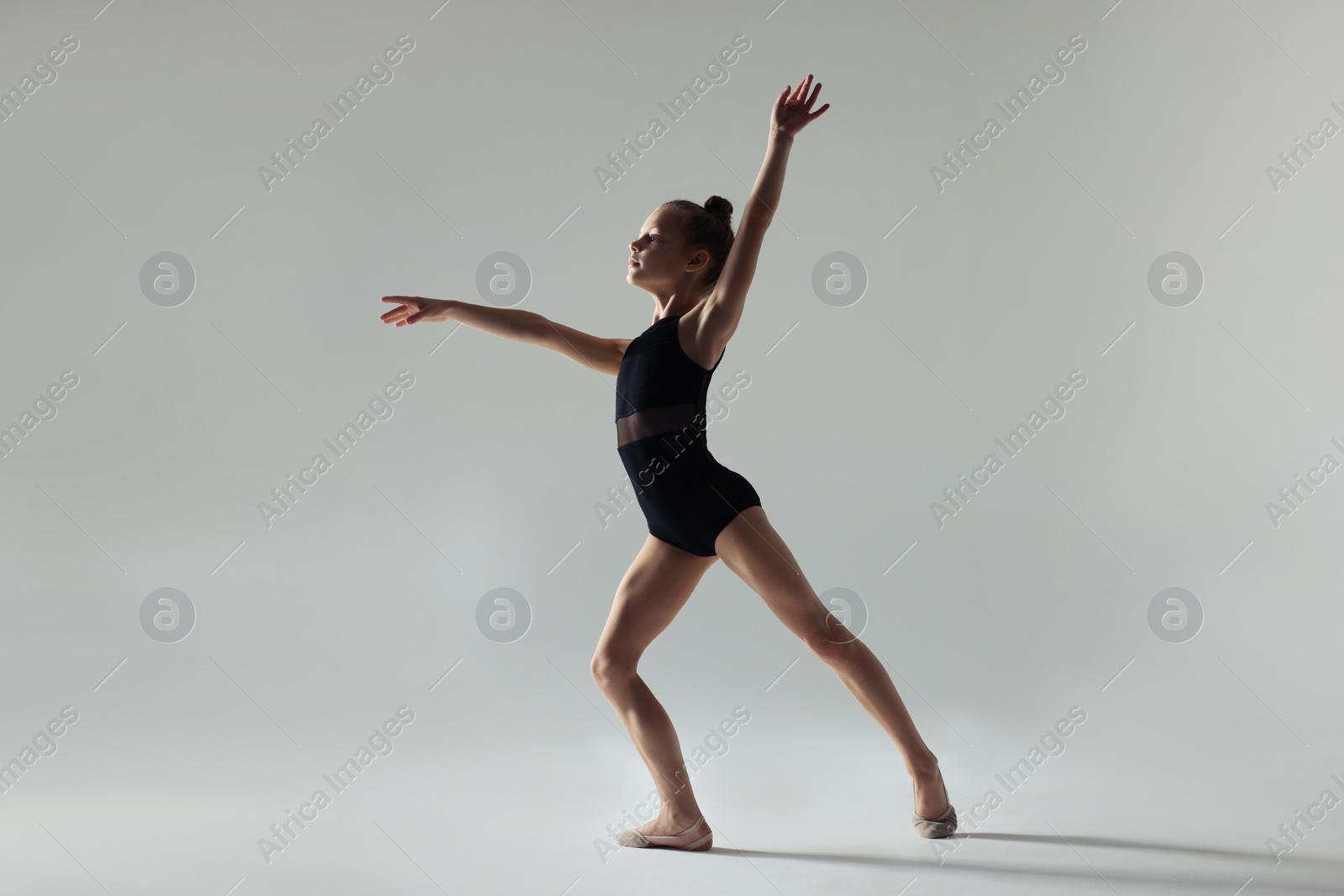 Photo of Cute little girl doing gymnastic exercise on white background