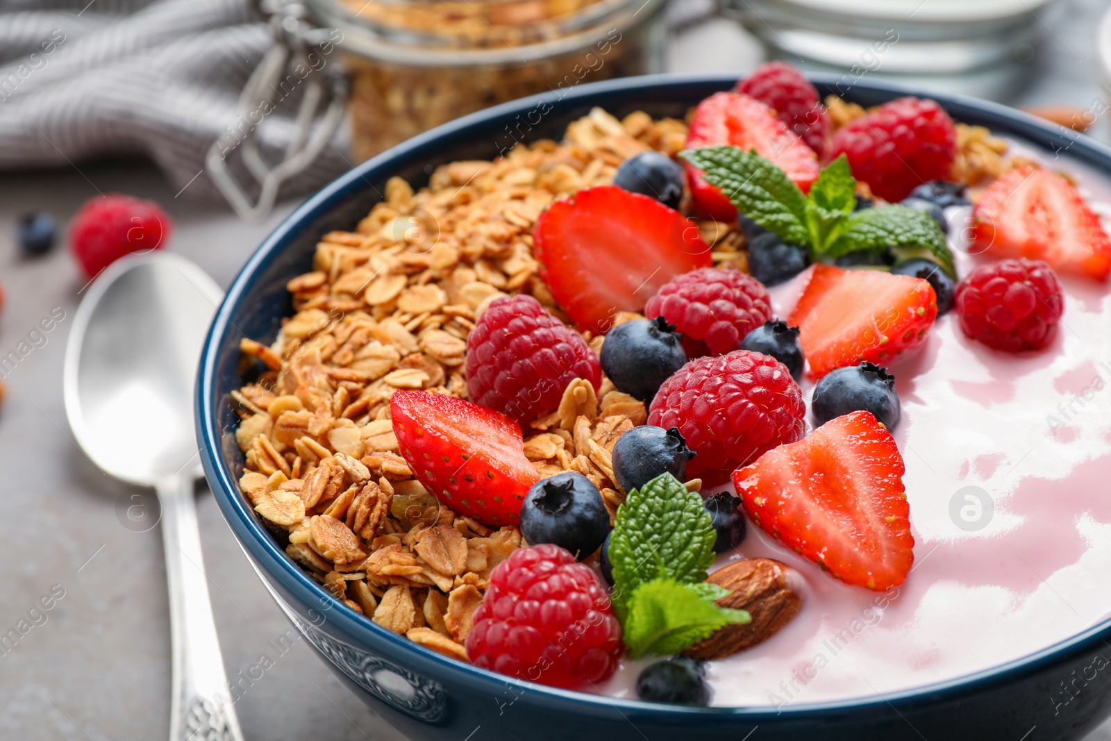 Photo of Tasty homemade granola with yogurt on grey table, closeup. Healthy breakfast