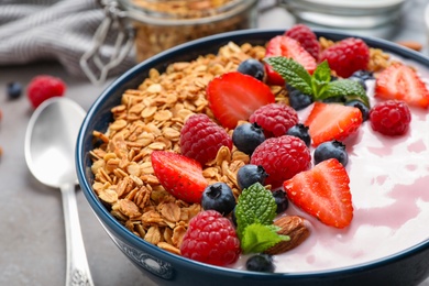 Photo of Tasty homemade granola with yogurt on grey table, closeup. Healthy breakfast