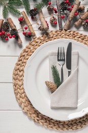 Plate, cutlery and Christmas decor on white wooden table, flat lay