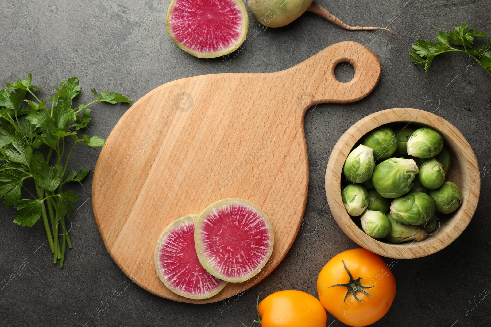 Photo of Flat lay composition with wooden cutting board and products on dark textured table