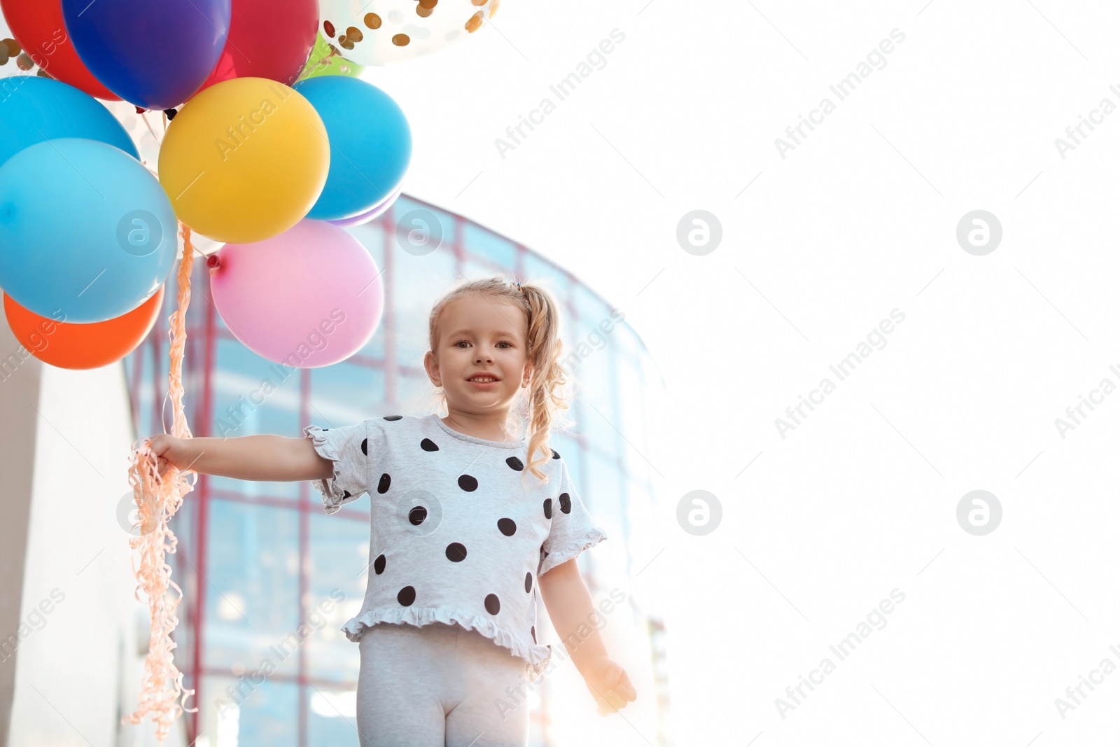 Photo of Cute little girl with colorful balloons outdoors on sunny day