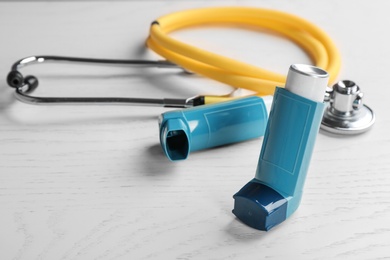 Photo of Asthma inhalers and stethoscope on white wooden background