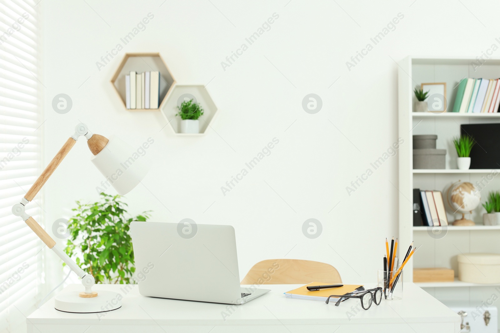 Photo of Beautiful workplace with comfortable desk, laptop and stationery at home