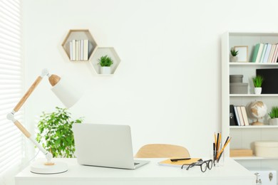 Photo of Beautiful workplace with comfortable desk, laptop and stationery at home