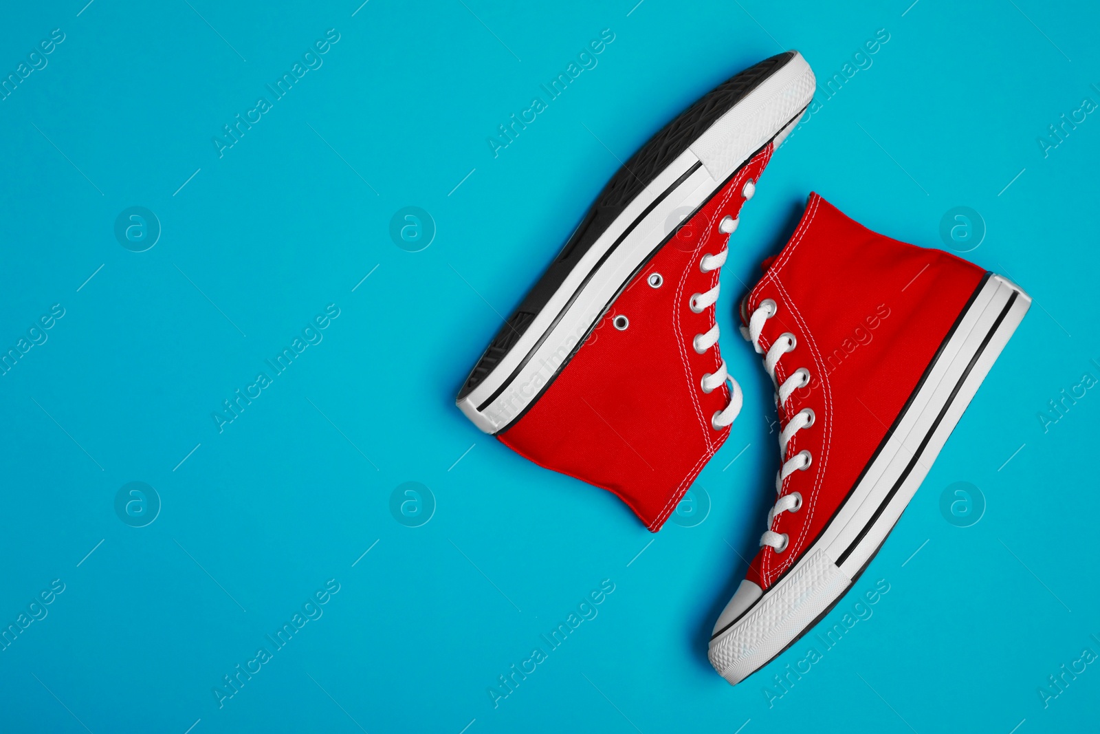 Photo of Pair of new stylish red sneakers on light blue background, flat lay. Space for text