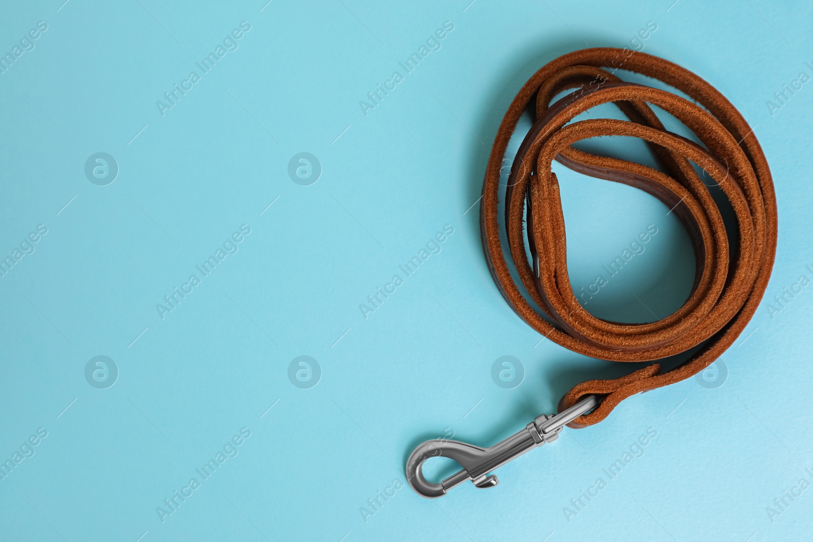 Photo of Brown leather dog leash on light blue background, top view. Space for text