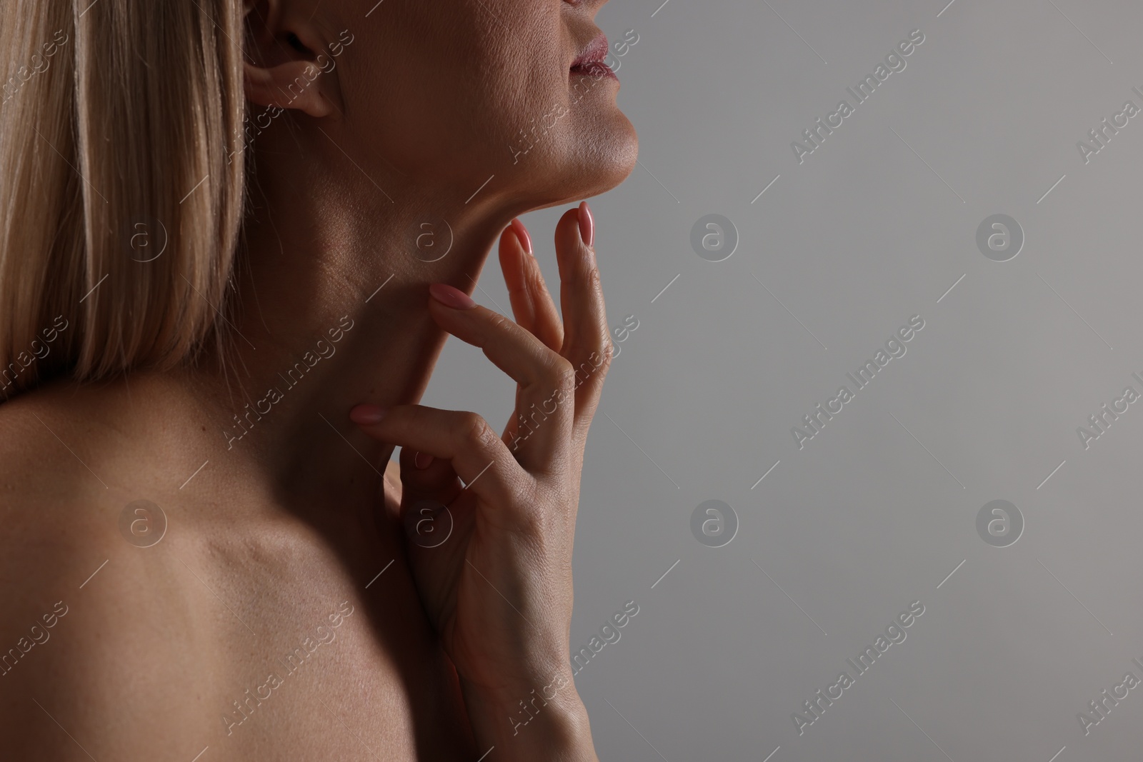 Photo of Woman touching her neck on grey background, closeup. Space for text