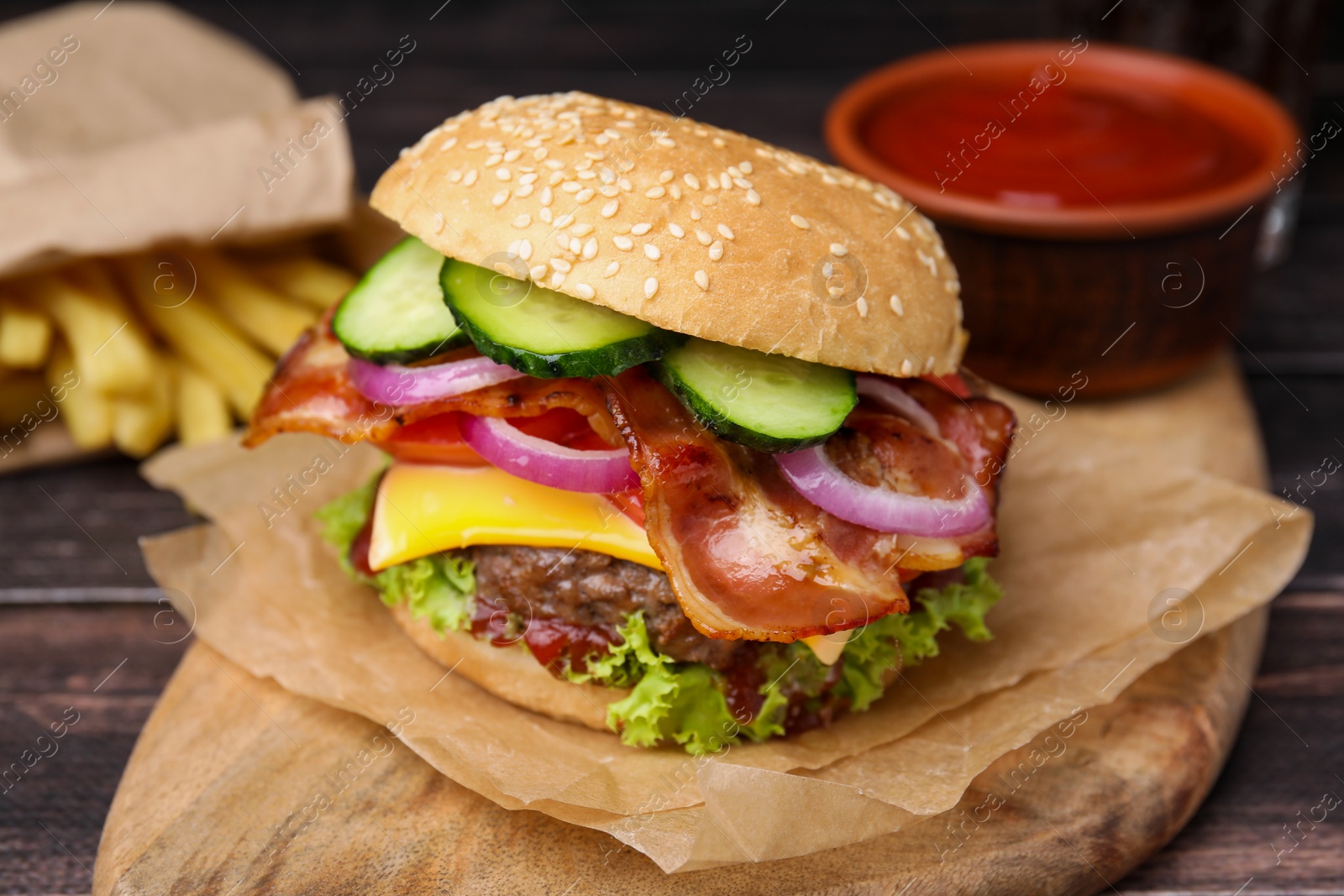 Photo of Tasty burger with bacon, vegetables and patty on wooden table, closeup