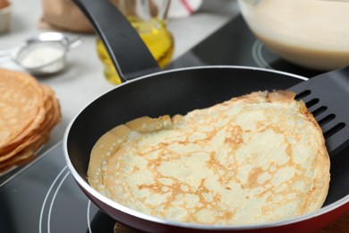 Photo of Delicious thin pancake in frying pan on induction stove, closeup