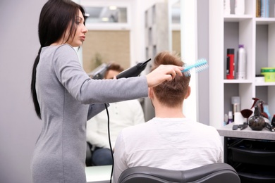 Professional female hairdresser working with client in salon