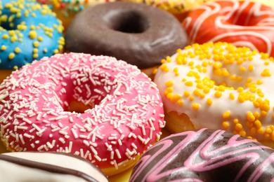 Photo of Delicious glazed donuts on yellow background, closeup