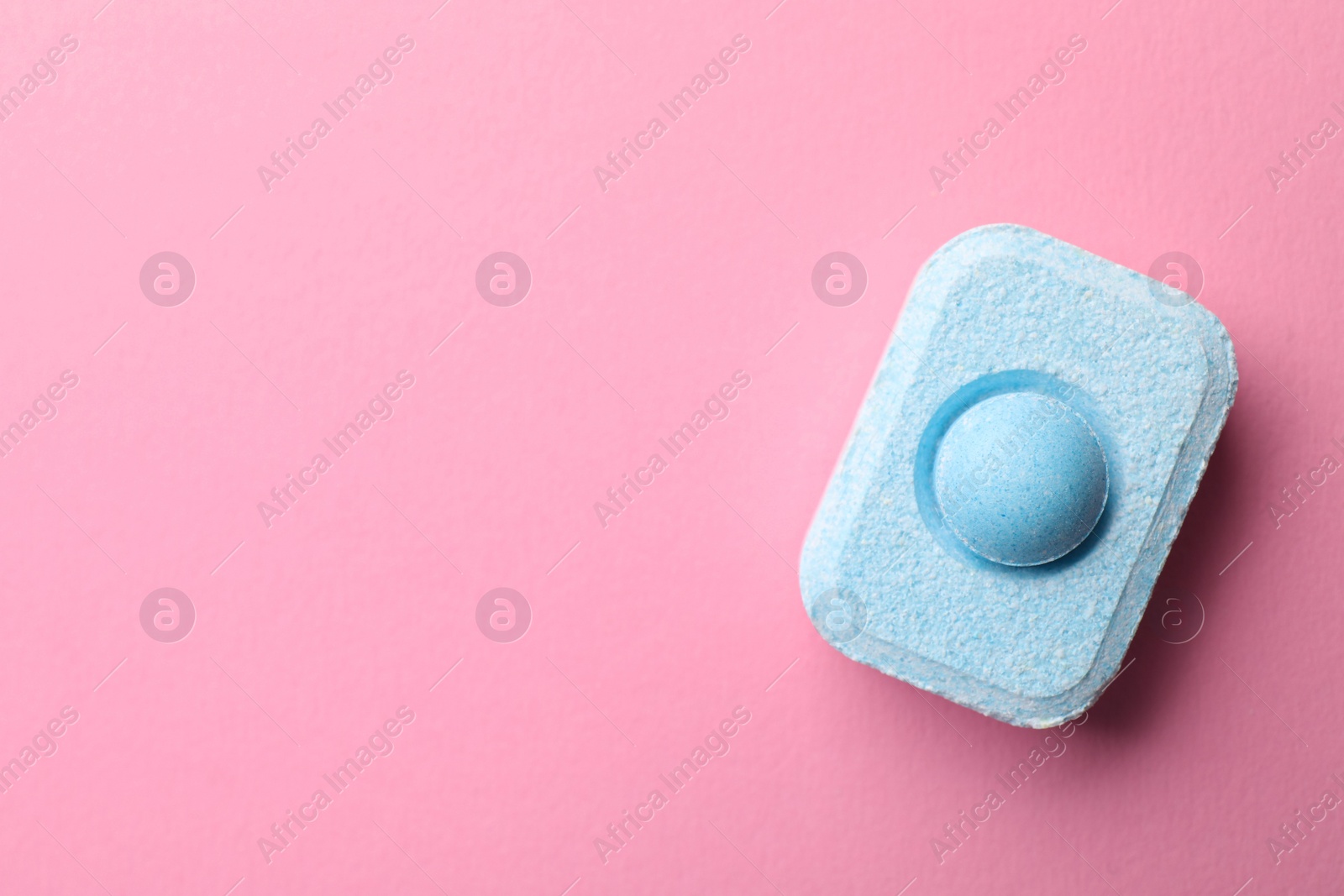 Photo of Water softener tablet on pink background, top view. Space for text