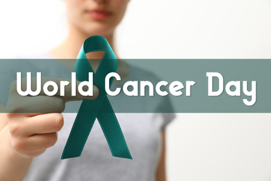 Image of Woman holding green ribbon against light background, closeup. World Cancer Day