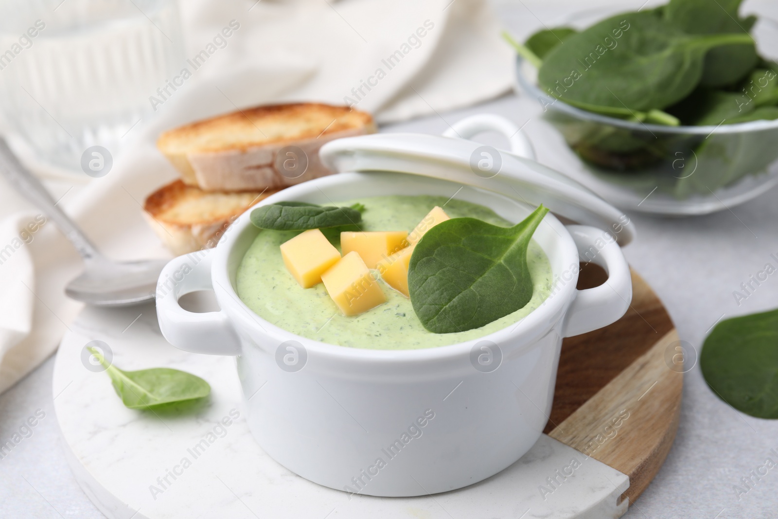 Photo of Delicious spinach cream soup with cheese in bowl served on light grey table