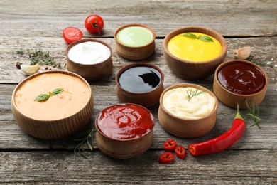 Photo of Many bowls with different sauces on wooden table