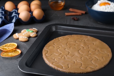 Photo of Making homemade gingerbread man cookies in baking dish on table, closeup