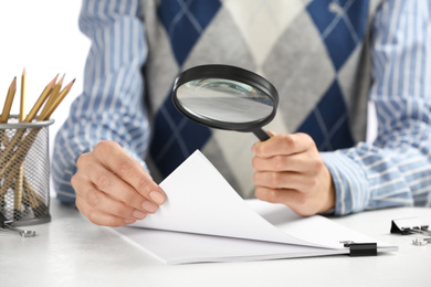 Woman using magnifying glass at table, closeup