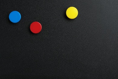 Photo of Bright magnets on black background, top view with space for text