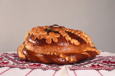 Photo of Rushnyk with korovai on grey background. Ukrainian bread and salt welcoming tradition